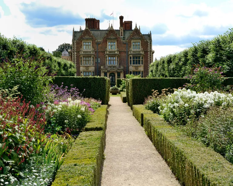 Jardins da rainha Elizabeth. Passarela em frente ao castelo, com blocos de flores e plantas dos dois lados.