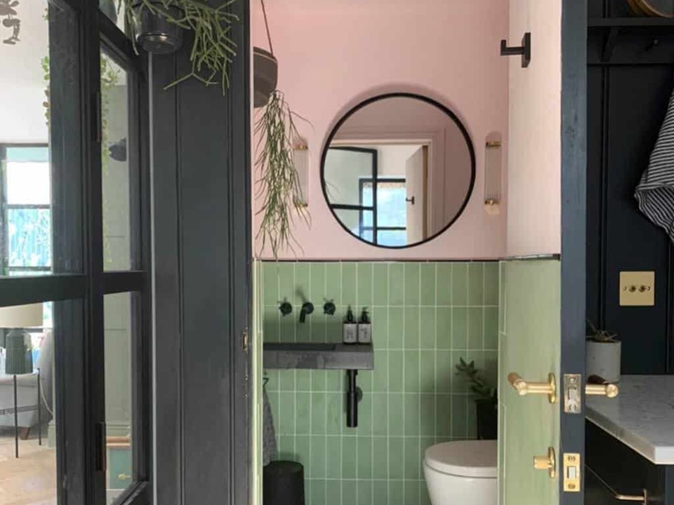 Lavabo com parede rosa e meia parede de azulejos verdes