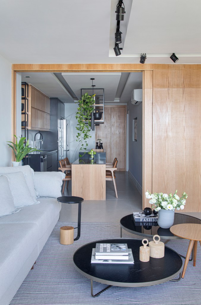 Sala integrada com cozinha; porta de correr de madeira ao fundo; sofá cinza