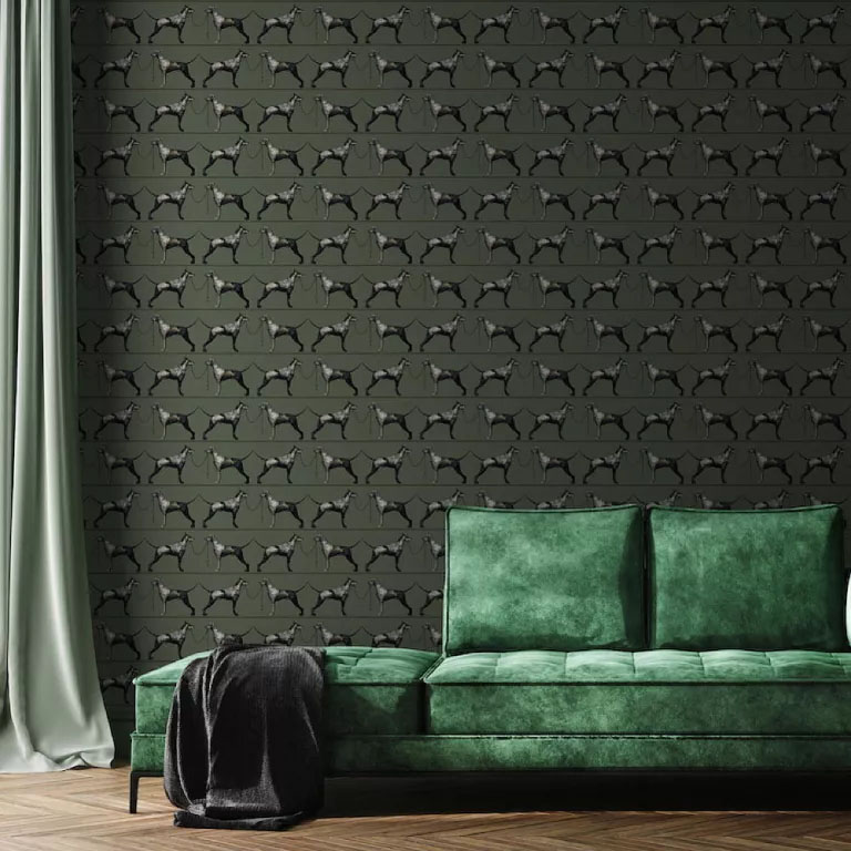 Sofá verde de veludo, em frente a uma parede com papel de parede preto com uma estampa que se repete em todo o material.