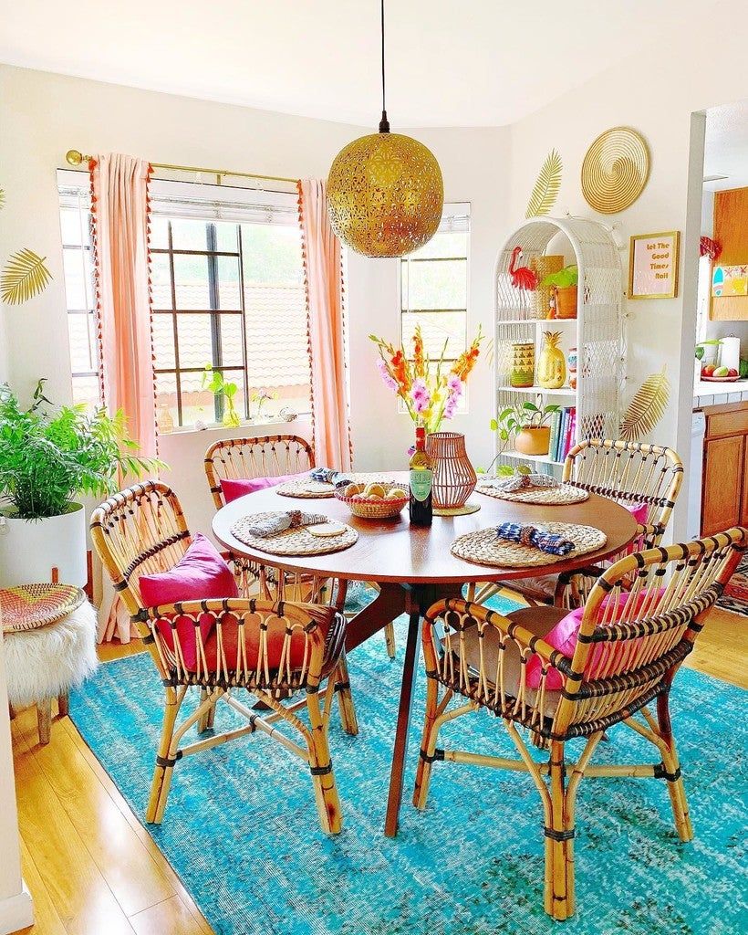 Sala de jantar em estilo boho; mesa redonda; quatro cadeiras de vime; luminária e tapete azul