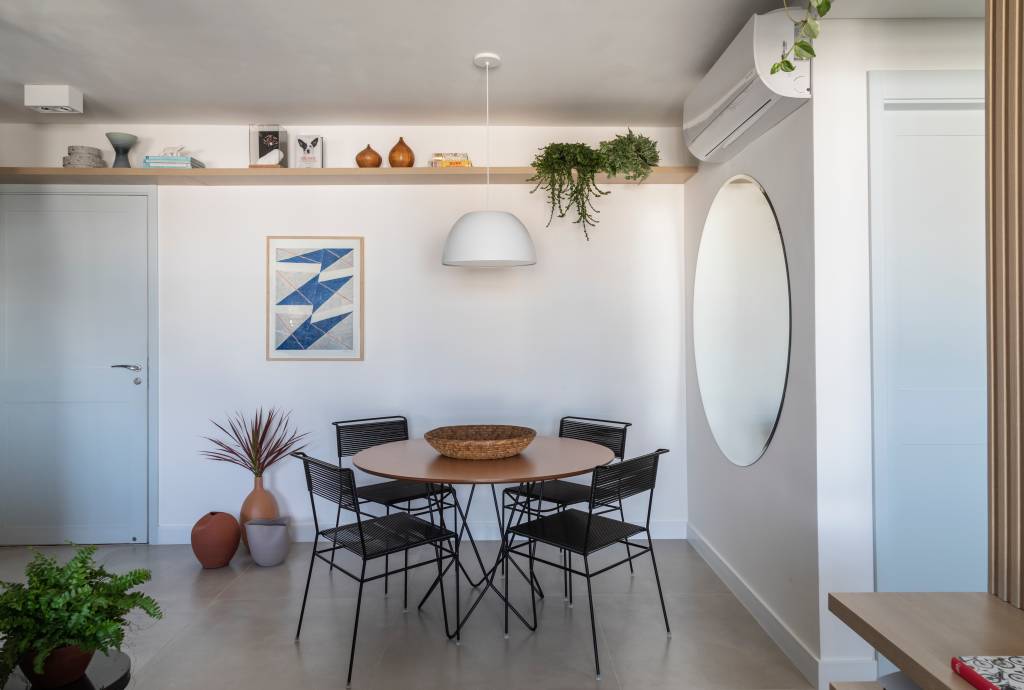 Sala de jantar com mesa redonda de quatro lugares; espelho redondo