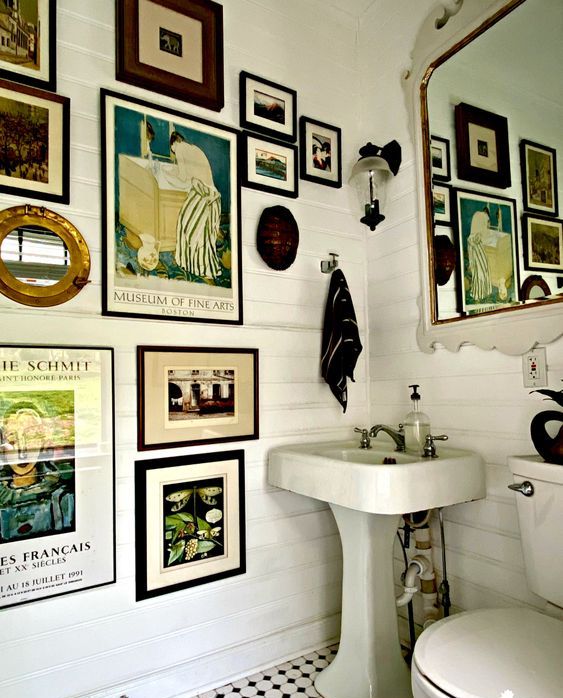 Banheiro com uma parede repleta de quadros.