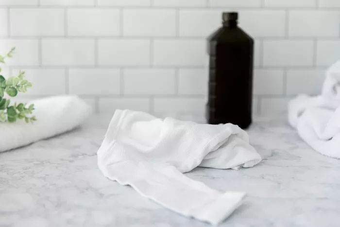 Frasco de água oxigenada ao lado de uma toalha.