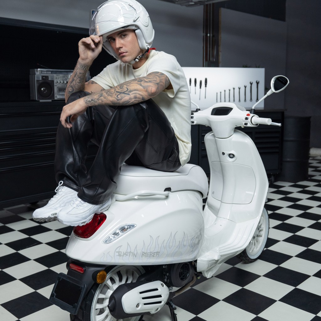 Justin Bieber posa sentado sobre scooter branca.