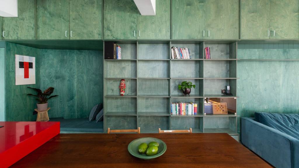 Sala com parede coberta de nichos e prateleiras verdes.