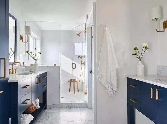 Banheiro com revestimentos em branco e armário em azul marinho.