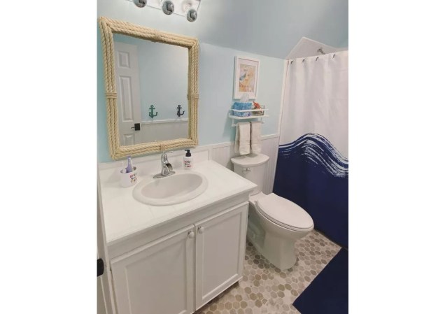 Os acessórios adornados com corda também são essenciais em qualquer banheiro litorâneo. Este espelho náutico é funcional e divertido.