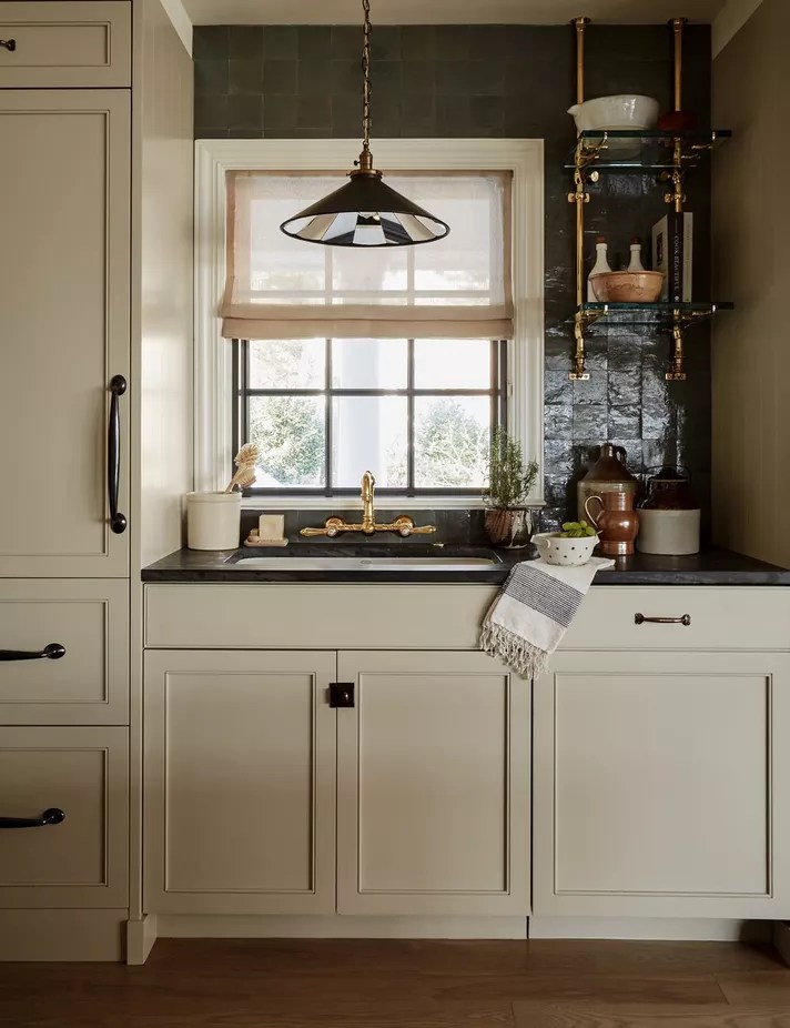 Cozinha com bancada e backsplash revestido por azulejos verde escuros.