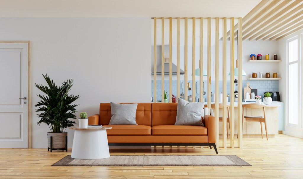 Sala com sofá laranja e parede divisória em ripas de madeira vazada.