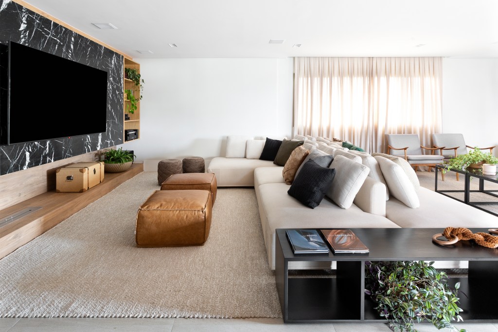 Sala de tv com sofá extenso e pufes