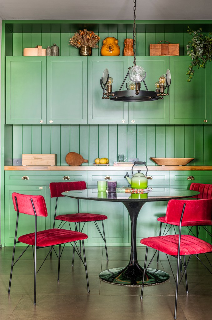Cozinha com marcenaria verde e mesa com cadeiras de veludo