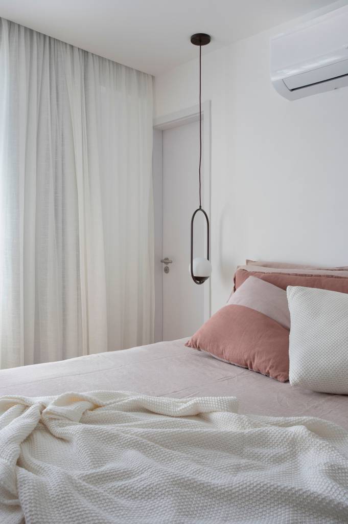 Quarto com almofadas rosas e luminária pendente