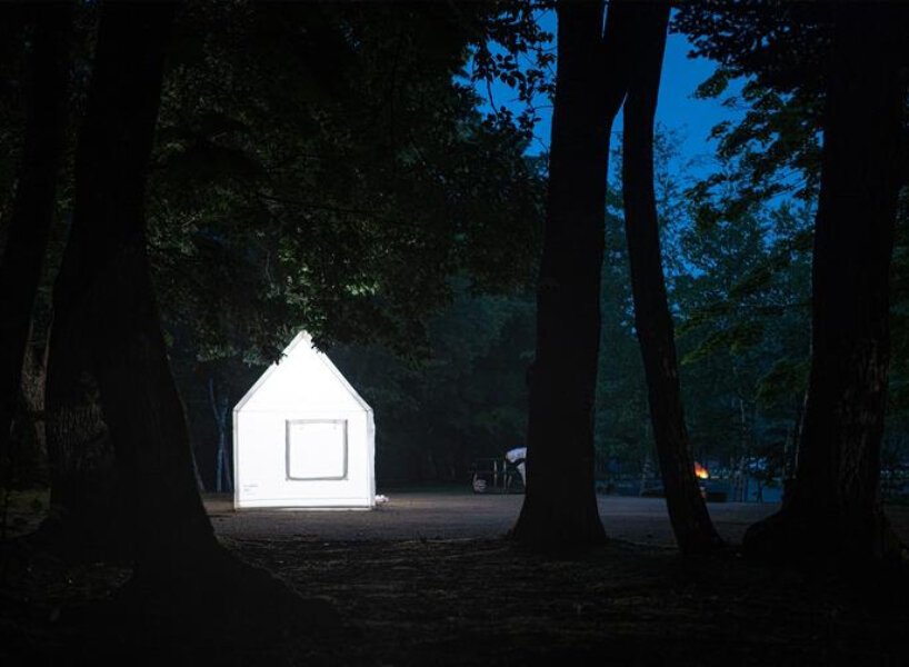Casa inflável branca brilhando na escuridão de uma bosque à noite.