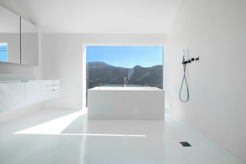 Banheiro todo branco com janela total com vistas para as colinas de Hollywood.