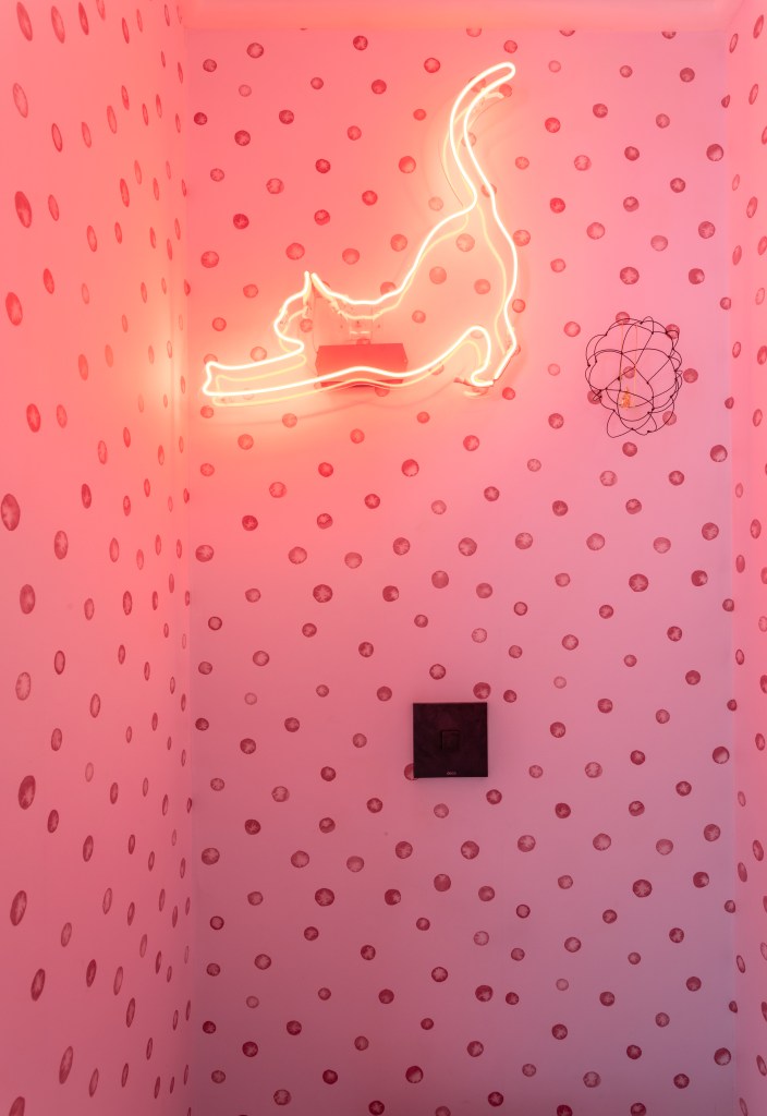 Lavabo com papel de parede rosa e gatinho neon