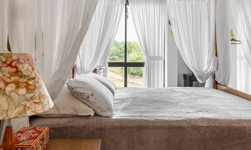 Quarto de casal com cama e janela com cortinas