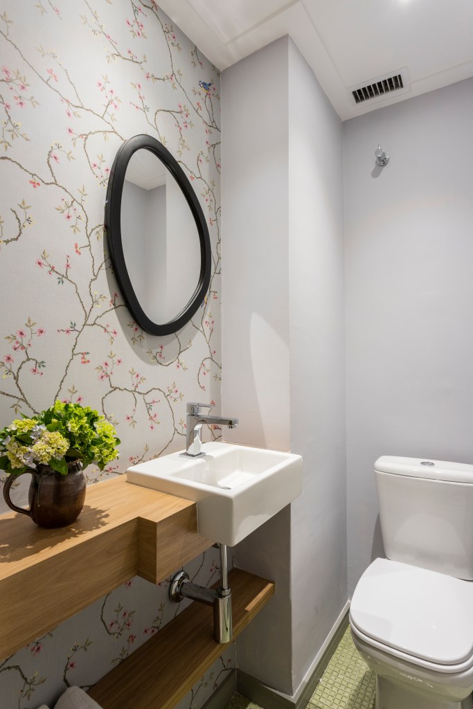 Lavabo com papel de parede floral e espelho em formato organico