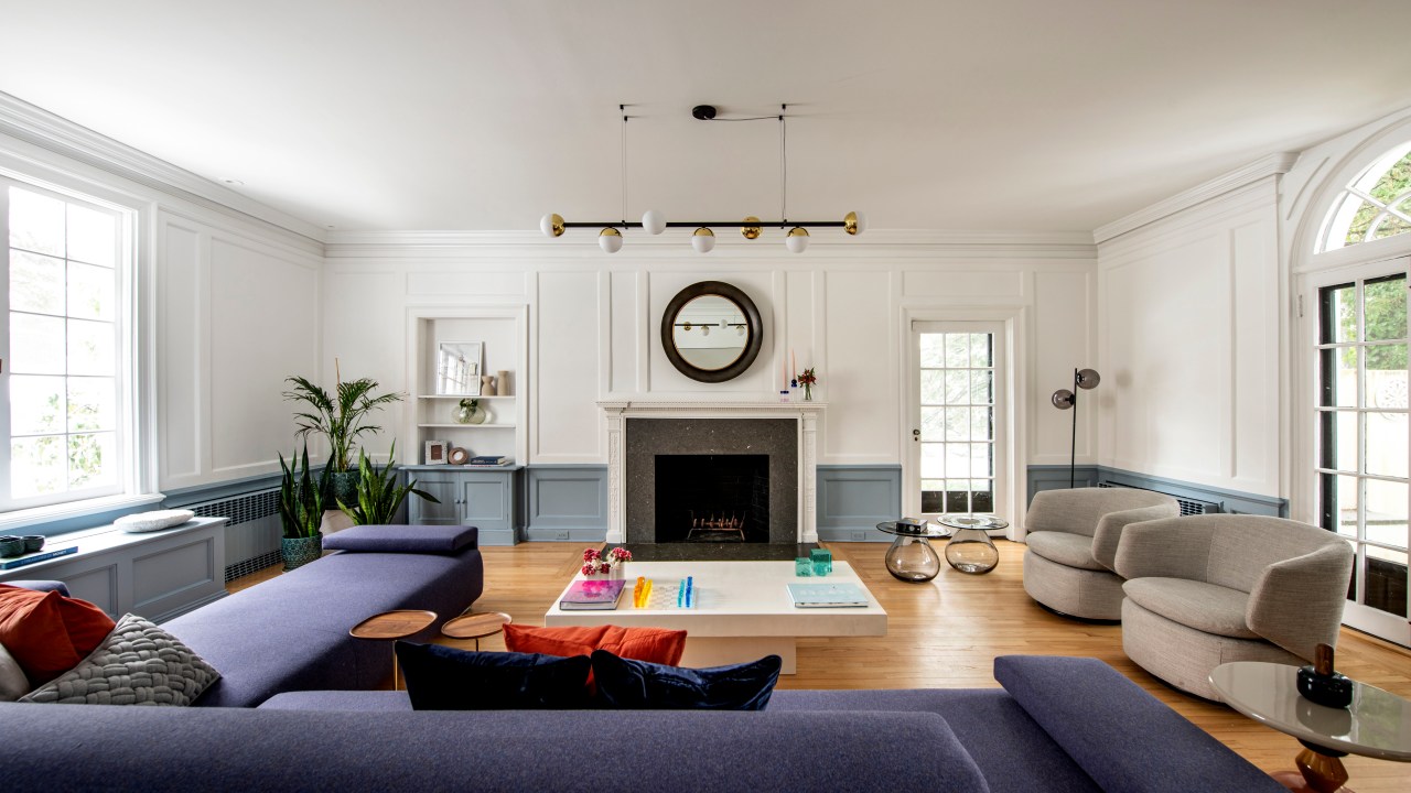 sala de estar com piso de madeira, lareira cinza, sofá azul em L