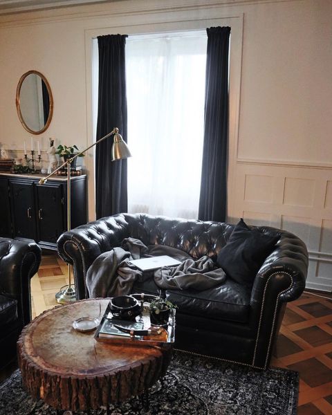 3-como-incorporar-a-estetica-dark-academia-na-decoracao Sofá preto com manta e mesa de centro de madeira