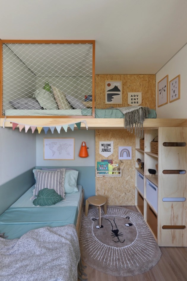 Quarto infantil com piso laminado, marcenaria com estantes e cama suspensa, além de diversos objetos de decoração infantil.