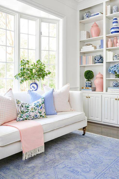Sala de estar com sofa branco e detalhes rosas pastel e azul claro