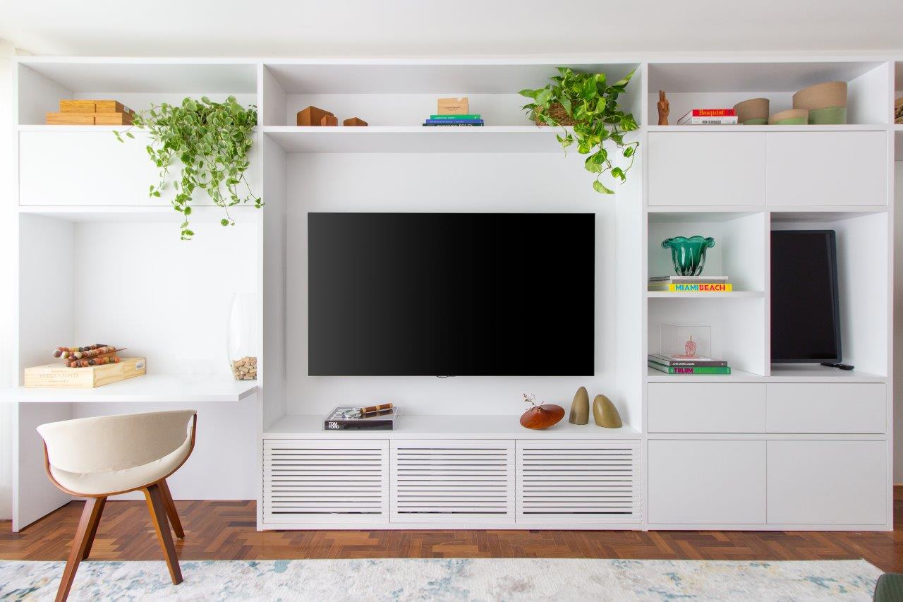 Marcenaria branca com tv, plantas e objetos decorativos