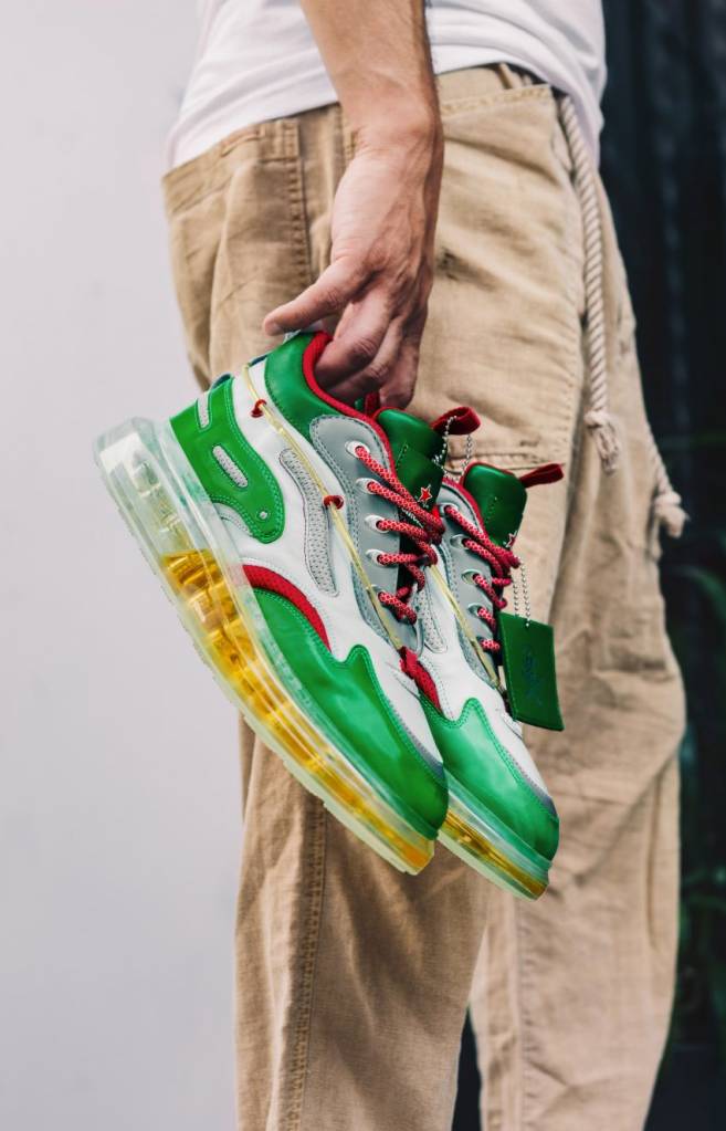 Os tênis da Heineken vêm com breja na sola Dezeen (3) Designer segura tênis em verde, vermelho e branco com sola transparente cheia de cerveja.
