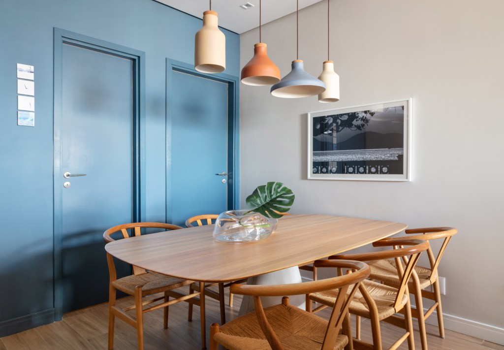 Sala de jantar com mesa em madeira e parede azul