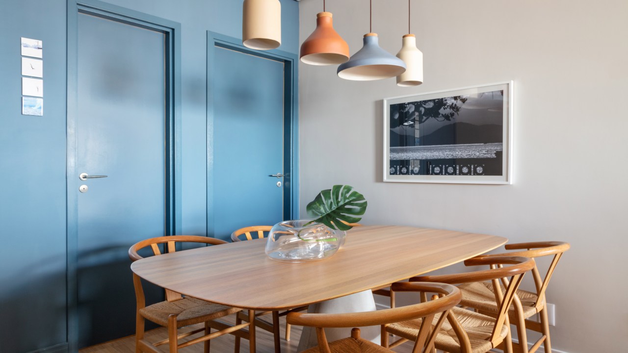 Sala de jantar com mesa em madeira e parede azul