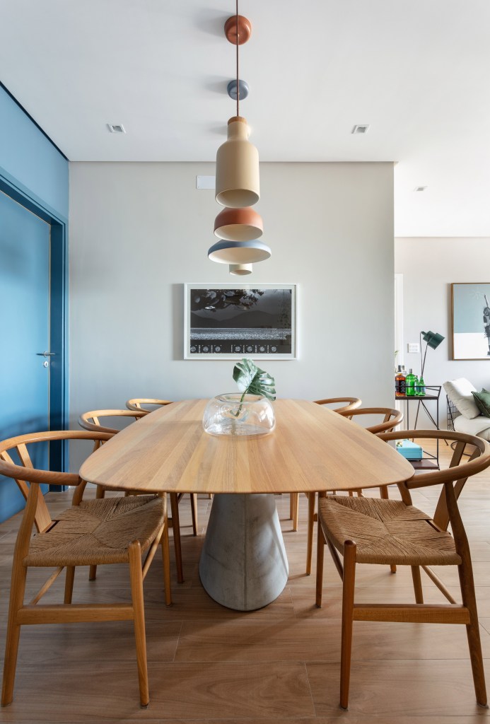 Sala de jantar com mesa em madeira e luminárias