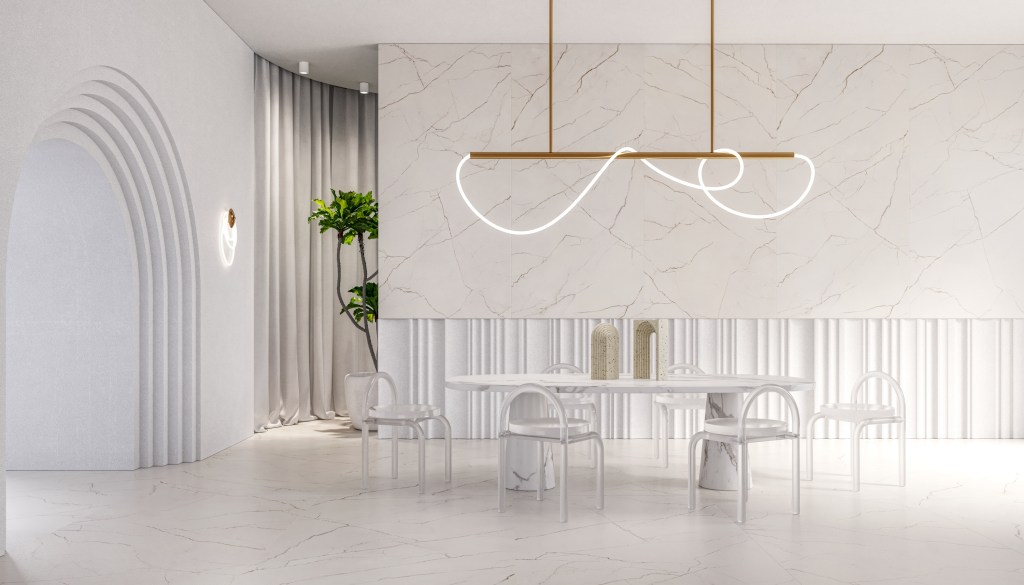 Mesa de jantar branca com cadeiras brancas em ambiente minimalista que tem piso e paredes revestidos com o mesmo porcelanato claro que lembra mármore.