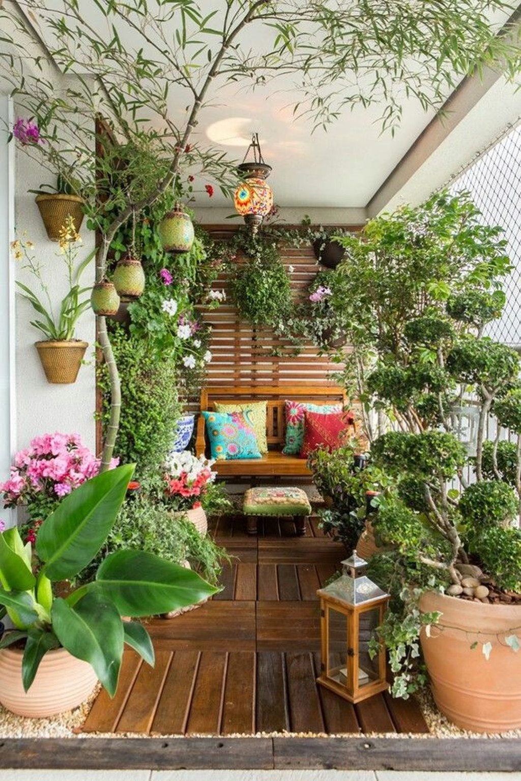 Varanda com folhagens e vasos de plantas; sofá com almofadas coloridas