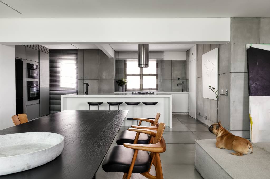 Sala integrada com cozinha; mesa de jantar preta; bancada branca
