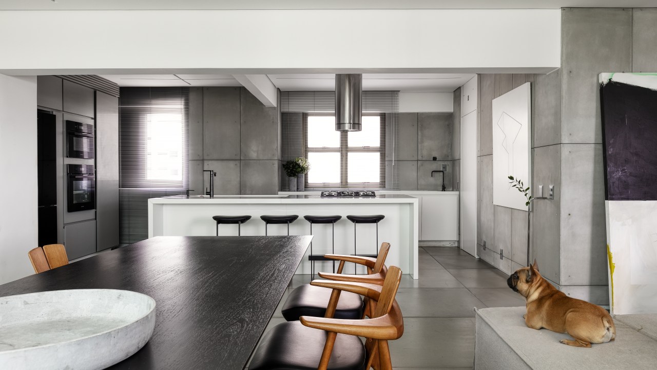 Sala integrada com cozinha; mesa de jantar preta; bancada branca