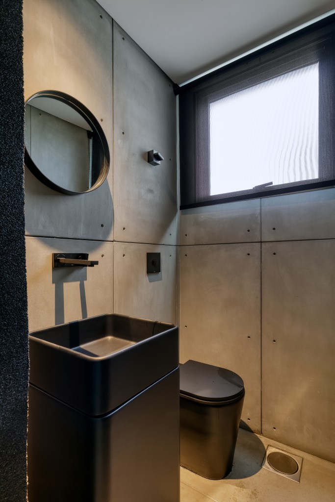 Banheiro com revestimento cimentício e louças pretas