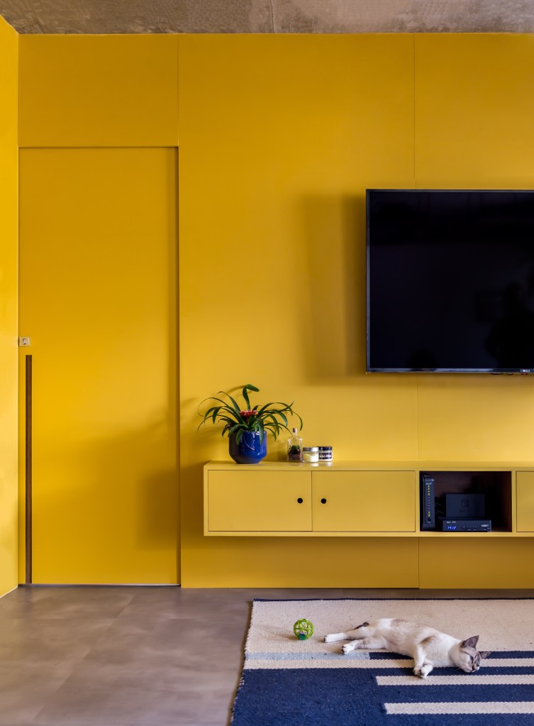 Sala de estar com tv e rack em marcenaria amarela