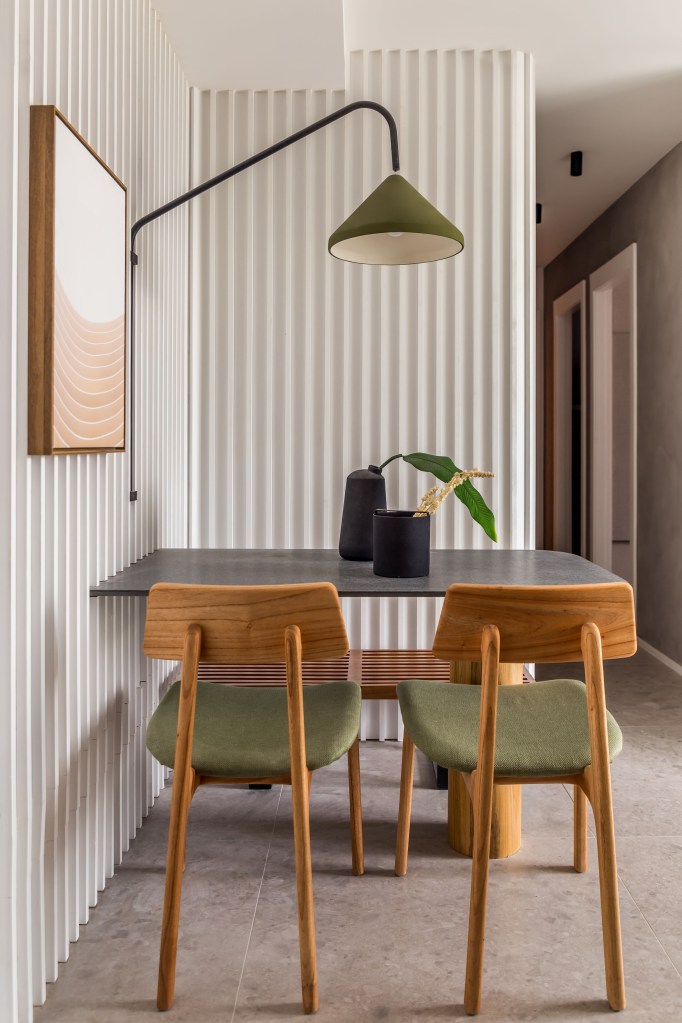 Sala de jantar com cadeiras em madeira; painel de madeira ripada branca
