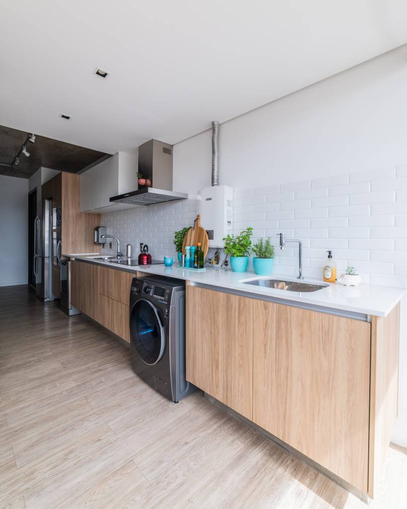 Na cozinha deste apartamento, o aquecedor a gás aparece de maneira discreta. Júlia Guadix utilizou o revestimento da mesma cor do aparelho, promovendo uma espécie de camuflagem. Os itens decorativos também ajudam a tornar o equipamento praticamente imperceptível.