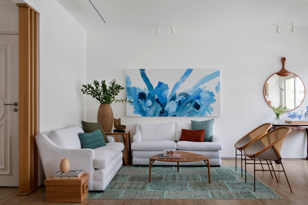 Sala de estar com sofá branco e quadro azul