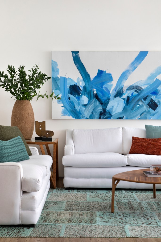 Sala de estar com sofá branco e quadro azul