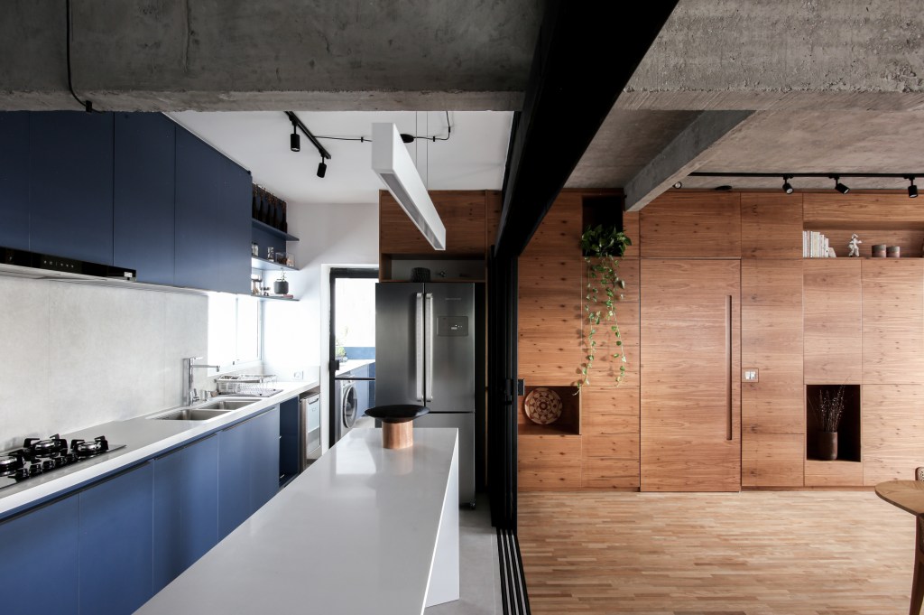 Cozinha com marcenaria azul integrada; porta de correr de vidro