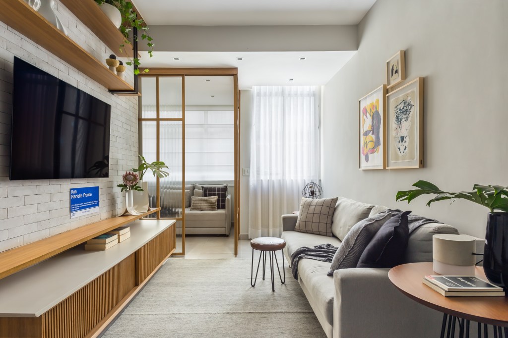 Sala de estar com porta de vidro; sofá cinza; tv, rack