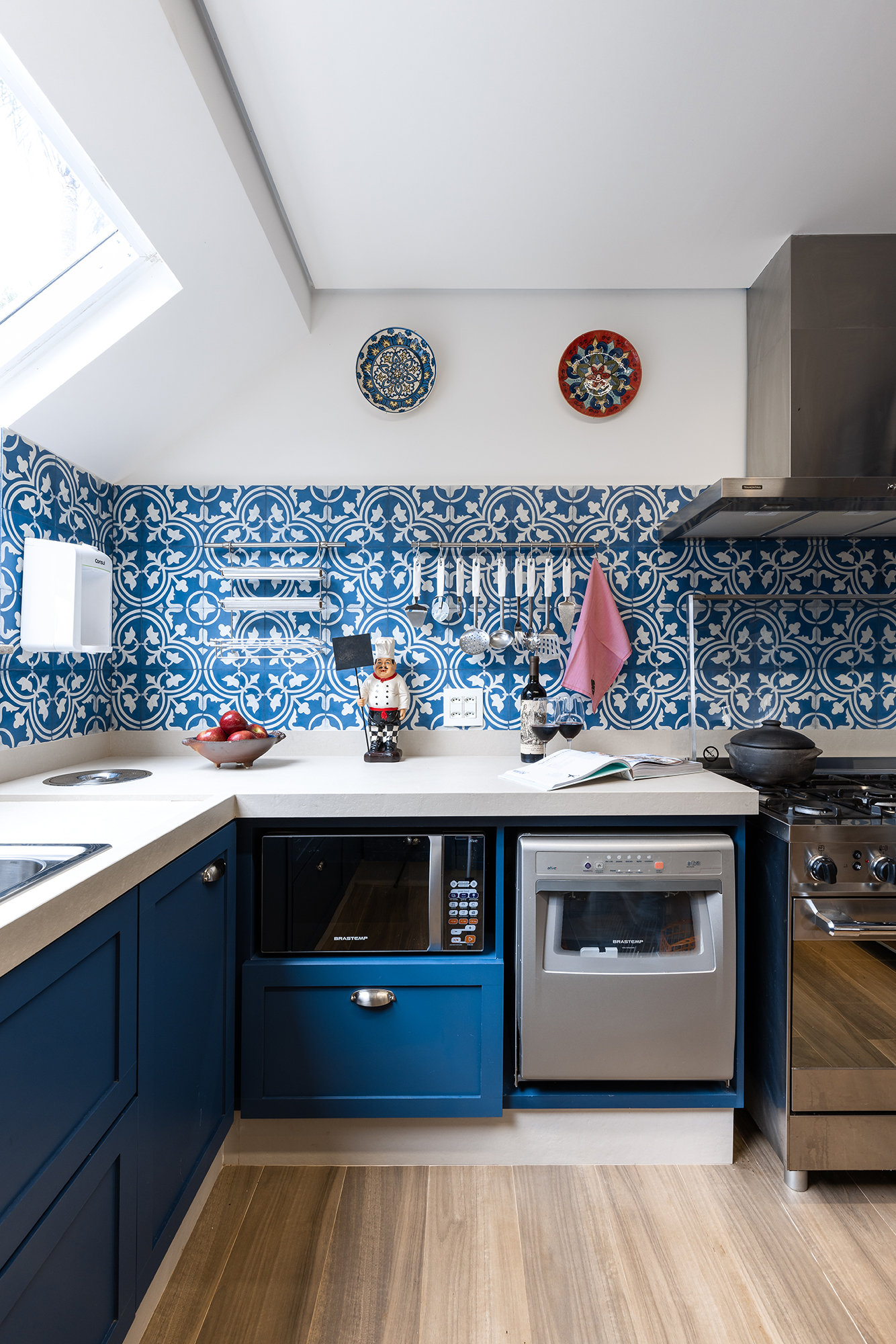 Cozinha com vista para natureza ganha marcenaria azul e claraboia