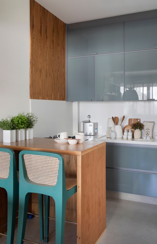 Cozinha integrada com marcenaria azul acinzentada e banquetas