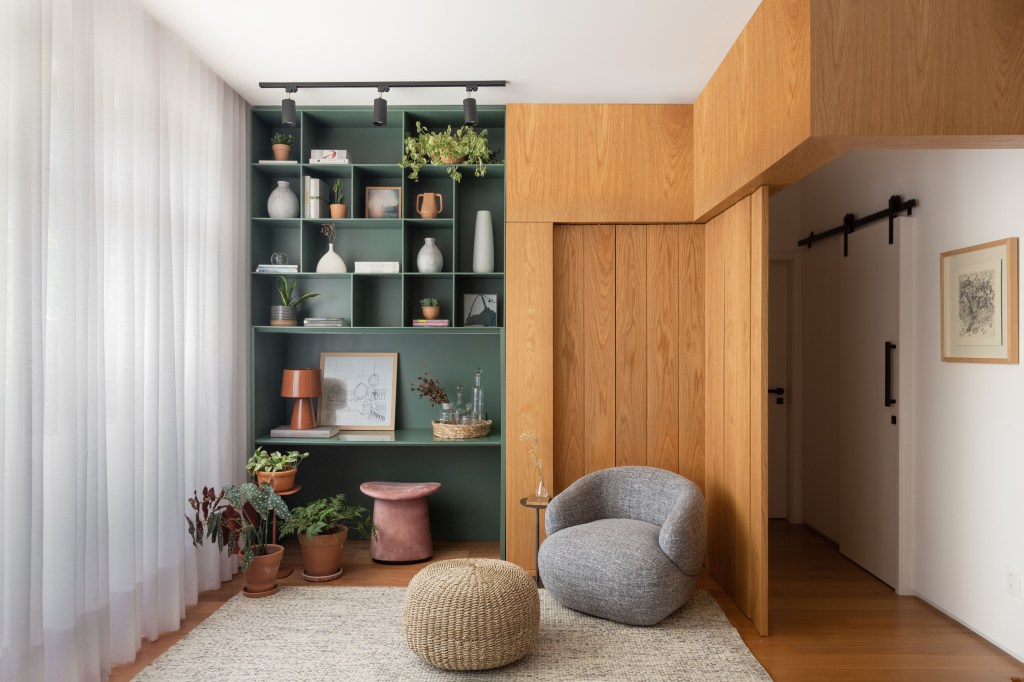 Sala de estar com divisórias em madeira; pufe e estante verde