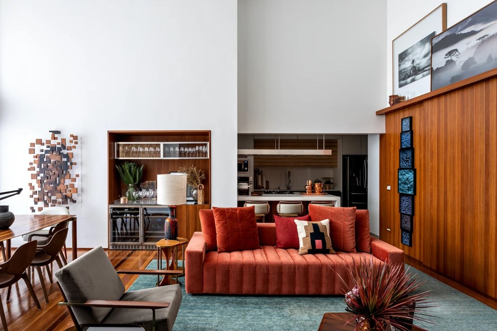 Sala de estar; sofá; paineis em marcenaria; cozinha integrada.
