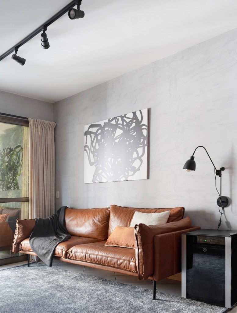 Sala de estar com sofá em couto e parede de cimento queimado