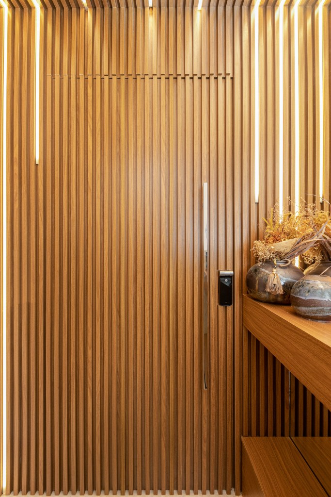 Hall de entrada com madeira ripada iluminado com fitas LED