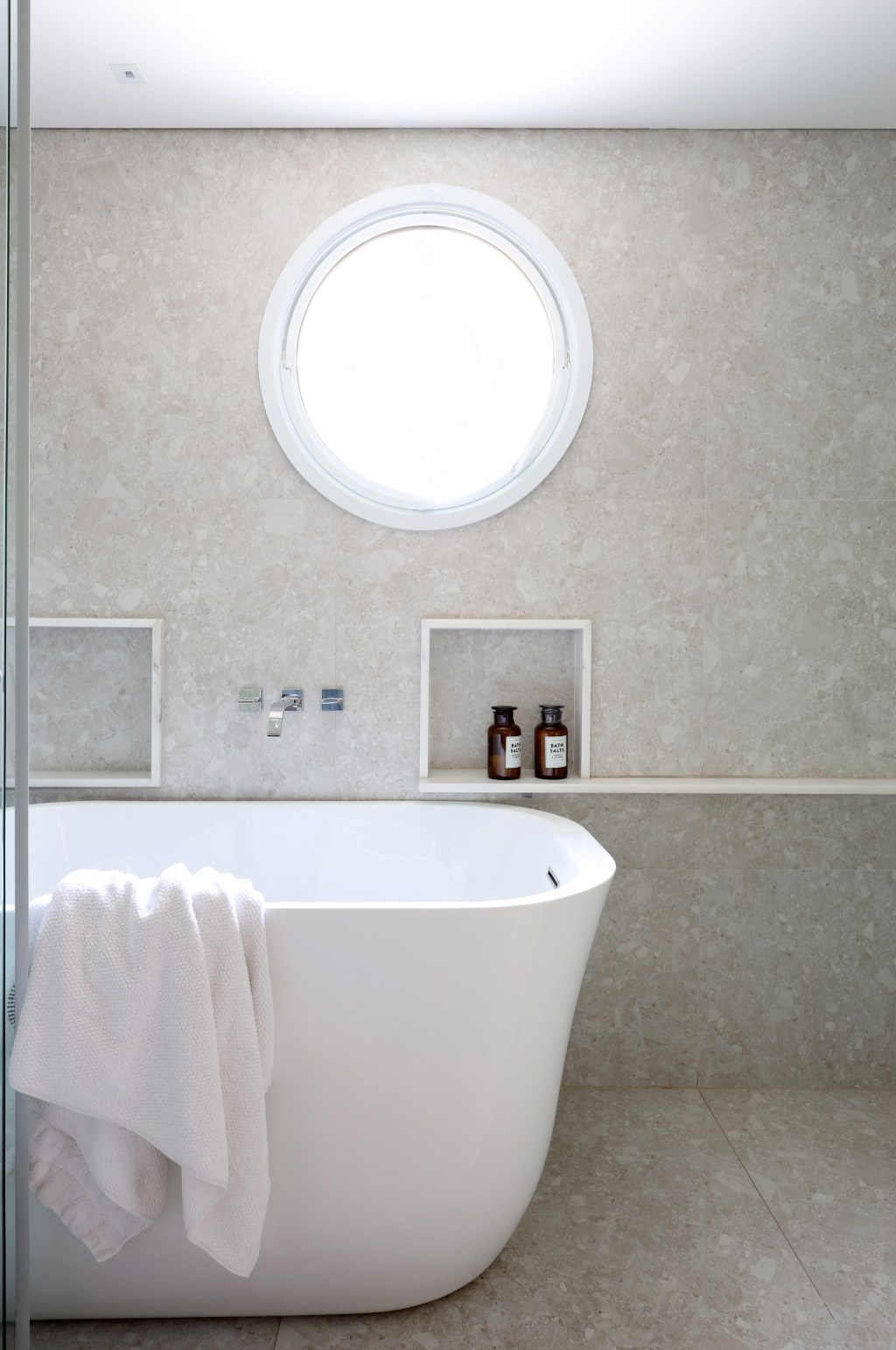 Banheiro com banheira solta e parede revestida de granilite cinza